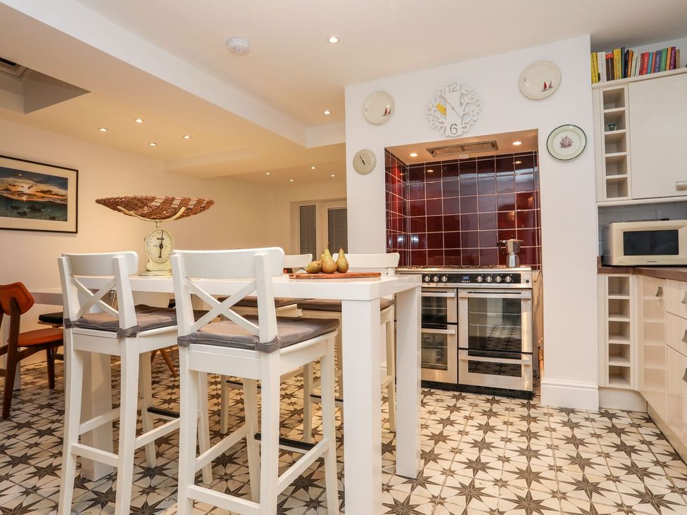 A kitchen with bar stools and kitchen appliances at Rhiwlas in Rhosneigr