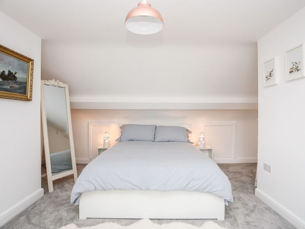 A bedroom with bed and mirror at Rhiwlas in Rhosneigr