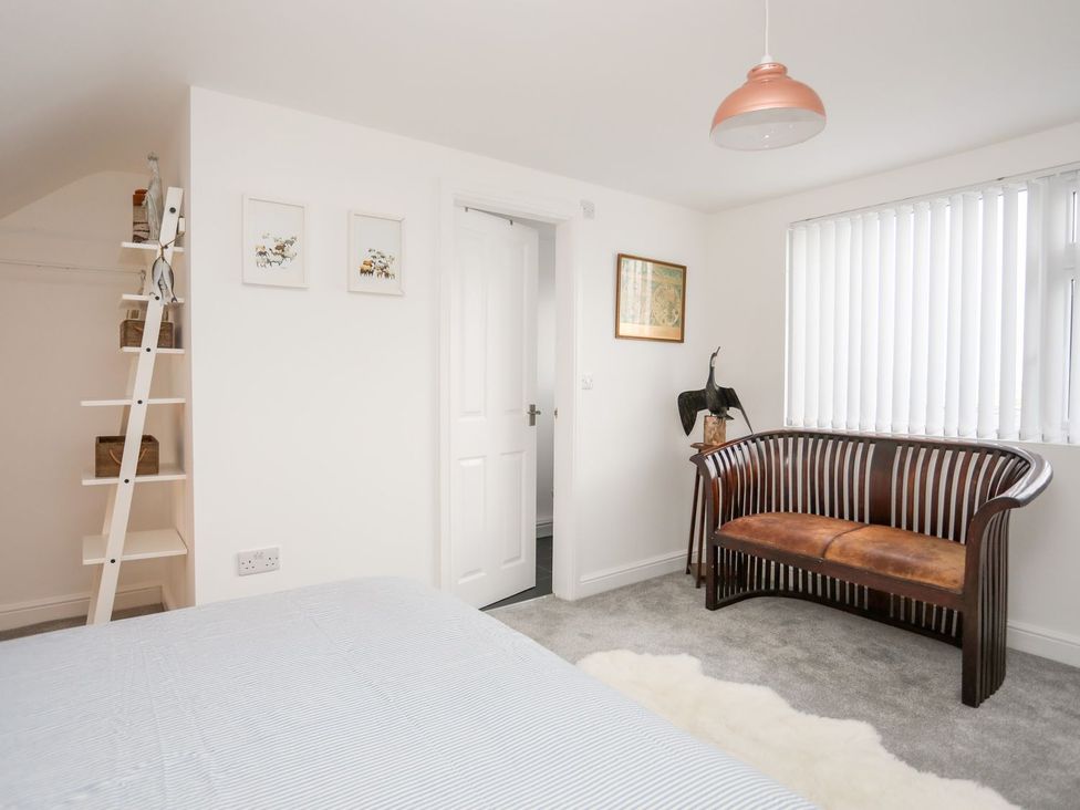 A bedroom with a bed and a wooden bench at Rhiwlas in Rhosneigr