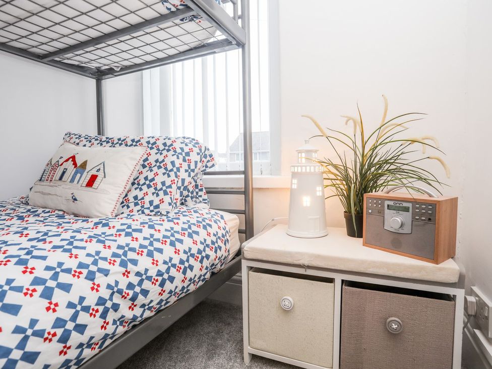 A bedroom with a bunk bed and nightstand at Rhiwlas in Rhosneigr