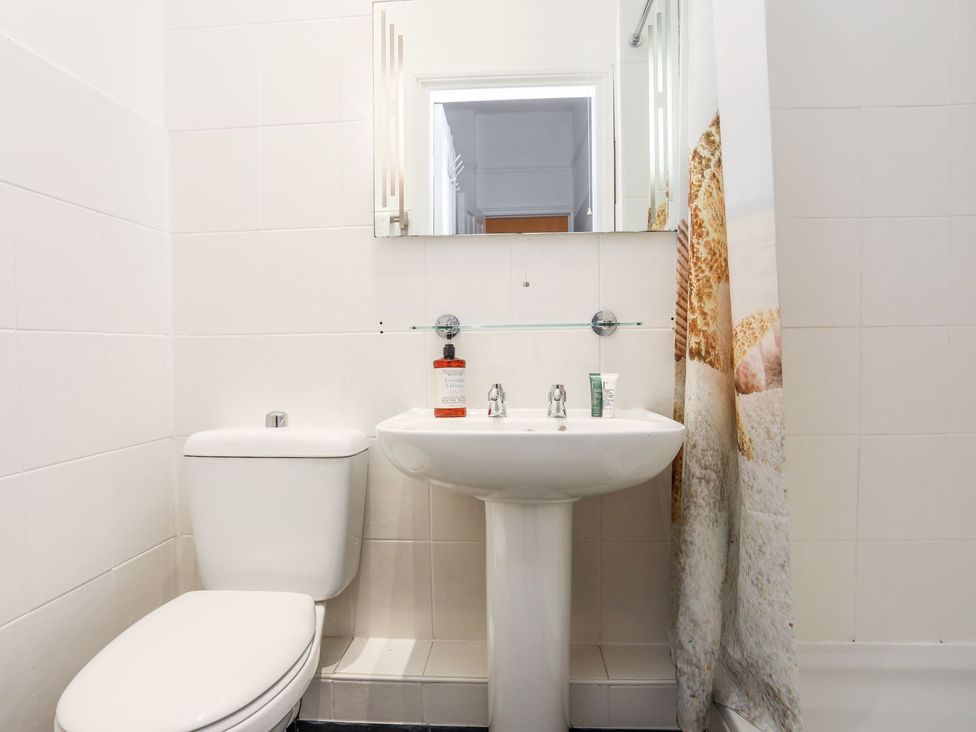 A bathroom featuring a toilet, sink, and shower curtain at Rhiwlas in Rhosneigr