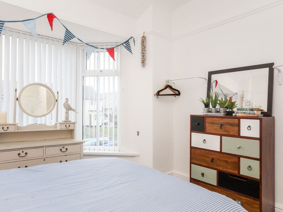 A bedroom featuring a bed and a dressing table with a mirror at Rhiwlas in Rhosneigr