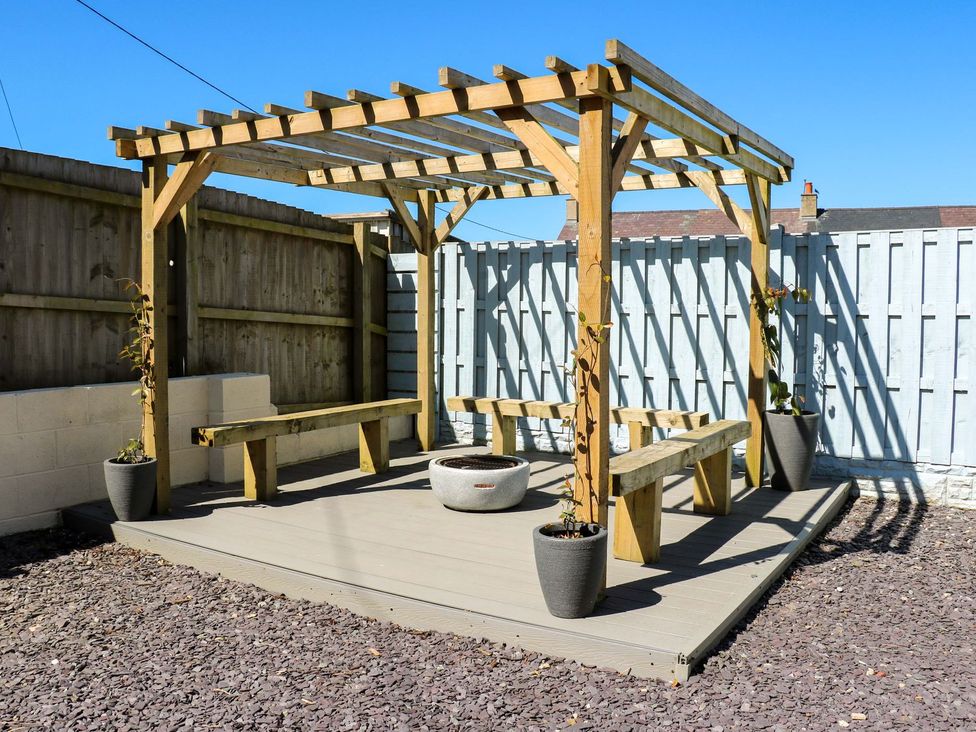 A garden with a pergola and benches at Rhiwlas in Rhosneigr