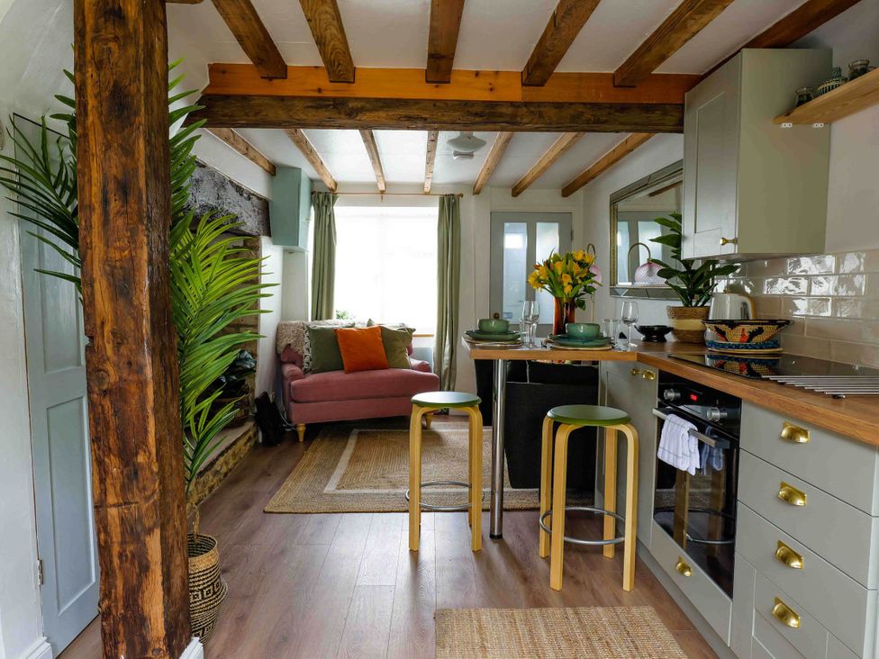 A kitchen with stools and a sofa at Cotswolds Cozy Cottage Retreat - pet friendly Finstock