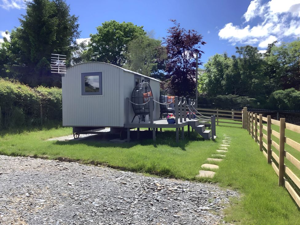 A shepherd hut with stairs and surrounding grass at The Shepherds Hut at Hafoty Boeth Corwen