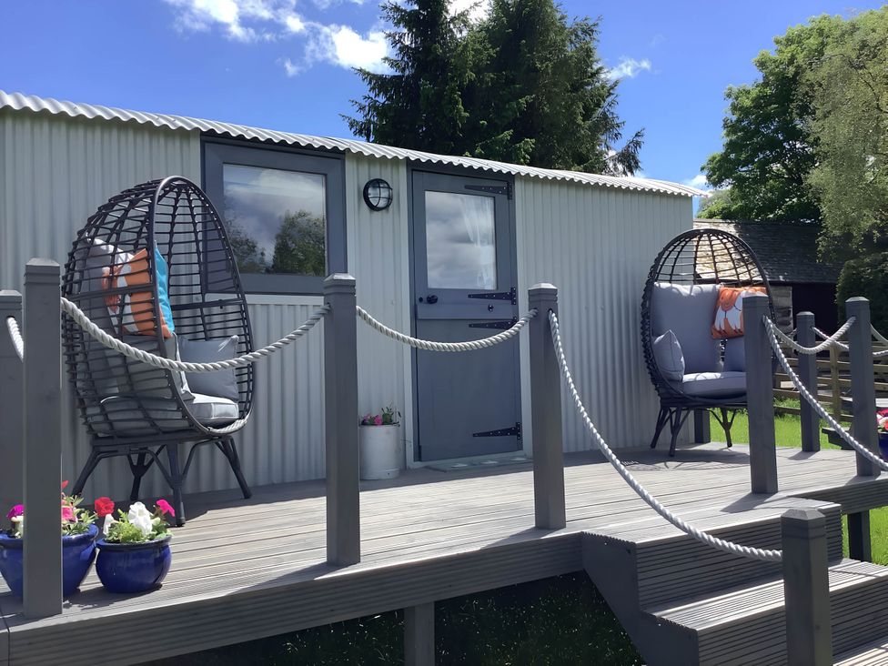 A deck with hanging chairs and door at The Shepherds Hut at Hafoty Boeth Corwen