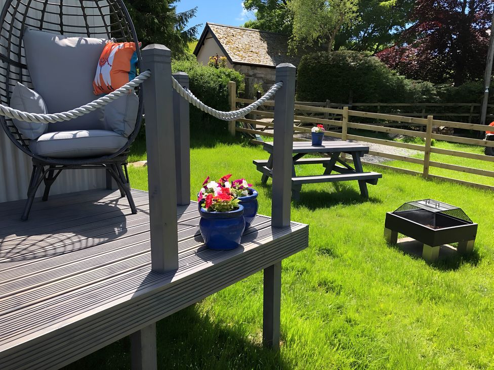 A garden with a hanging chair and picnic table at The Shepherds Hut at Hafoty Boeth Corwen