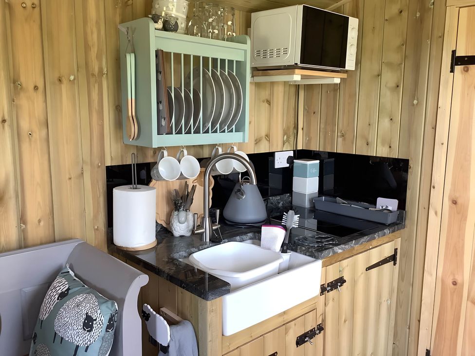 A kitchen with sink, microwave, and utensils at The Shepherds Hut at Hafoty Boeth Corwen