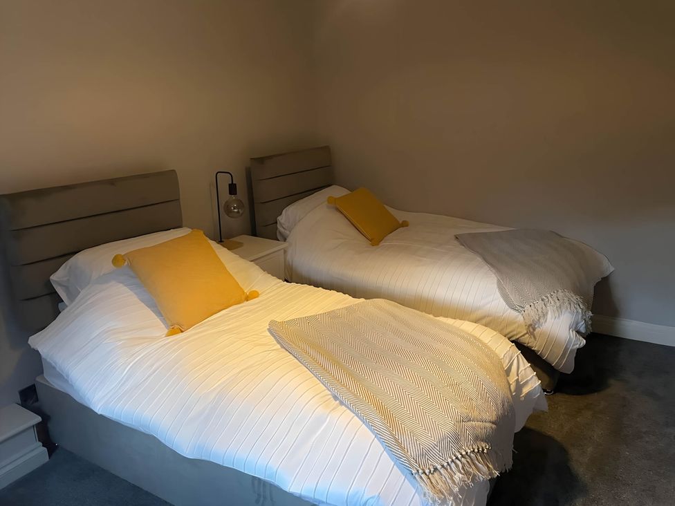 A bedroom with two beds and bedside table at Cosy Apartment above Village Pub