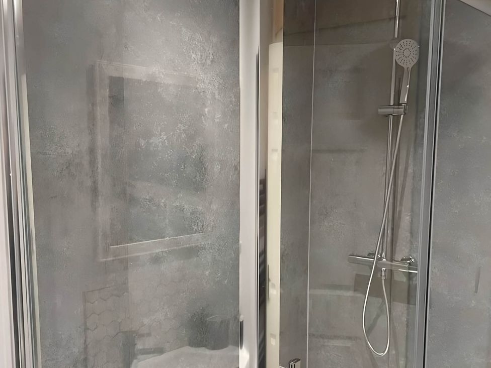 A shower area with glass panels and a showerhead at Cosy Apartment above Village Pub 