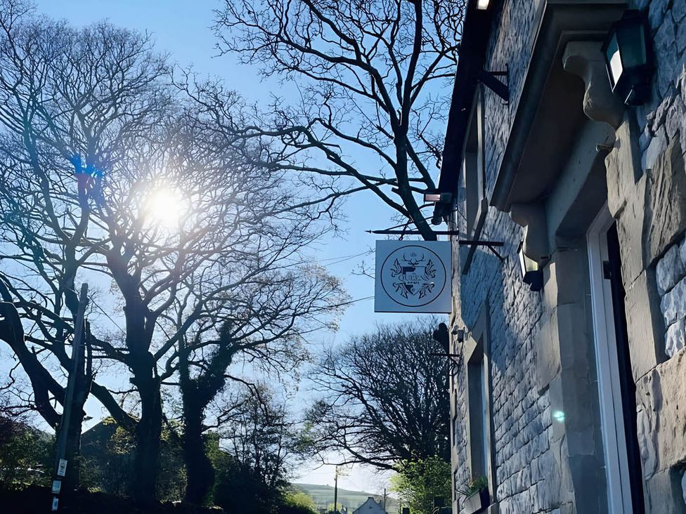 A building with a sign and trees at Cosy Apartment above Village Pub 