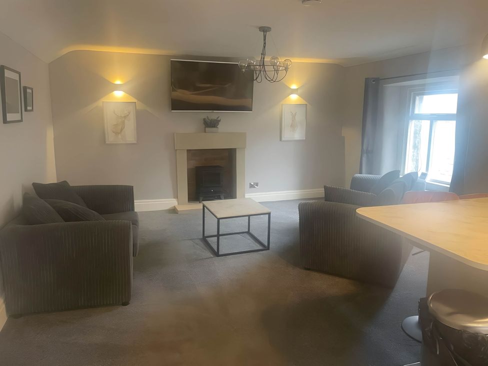 A living room with a sofa, coffee table, and television at Cosy Apartment above Village Pub