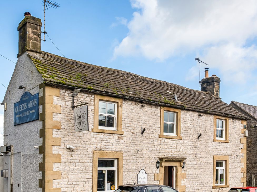 A pub building with a sign and a car outside at Queens Arms in Taddington
