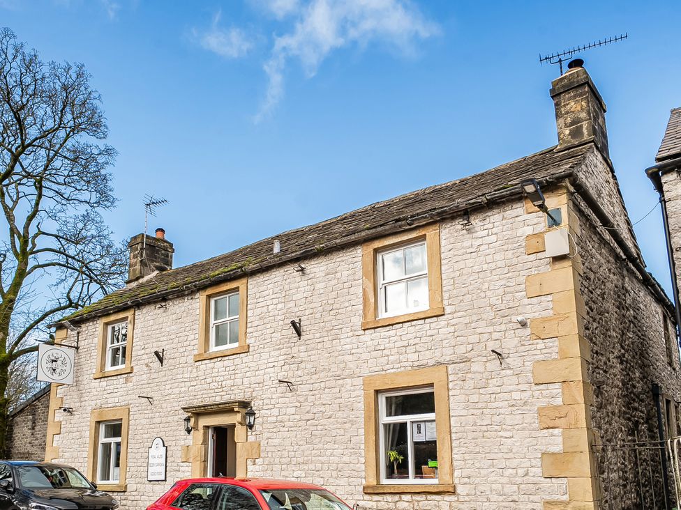 A stone building with windows and a sign at Cosy Apartment above Village Pub Taddington