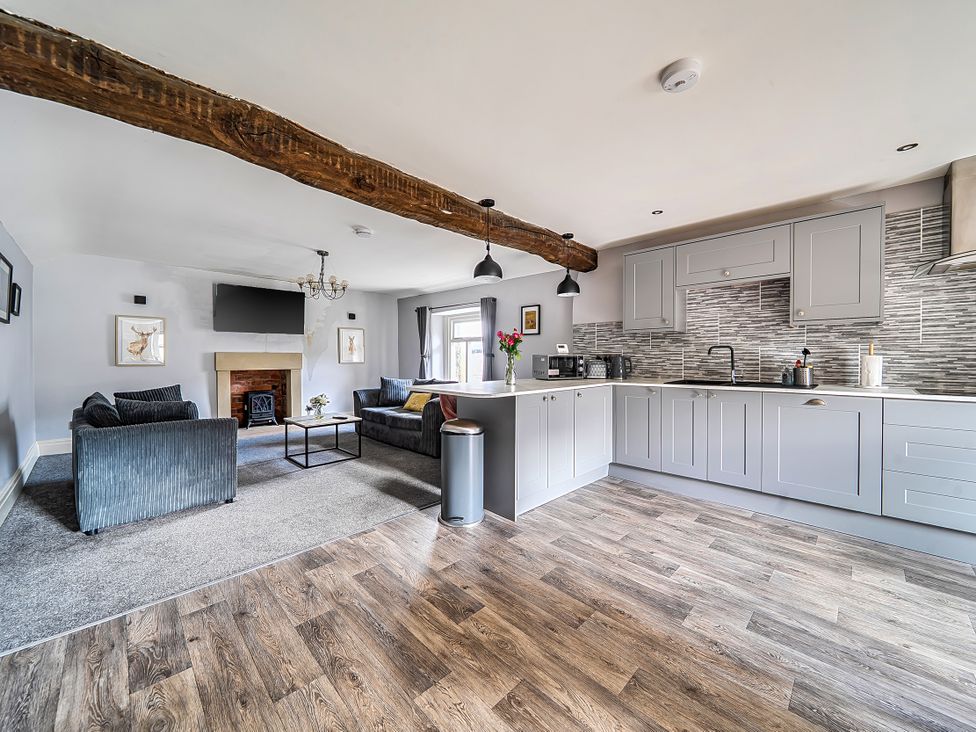 A living room and kitchen area with a fireplace and furniture at Cosy Apartment above Village Pub in Taddington