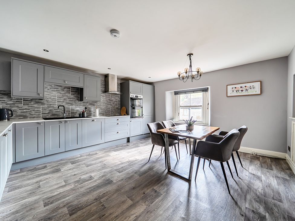 A kitchen with cabinets and a dining area at Cosy Apartment above Village Pub in Taddington