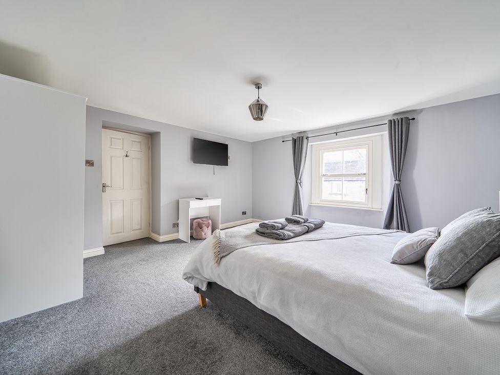 A bedroom with a bed and a television at Cosy Apartment above Village Pub Taddington