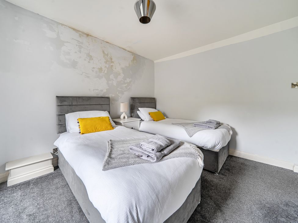 A bedroom with two single beds and a bedside lamp at Cosy Apartment above Village Pub in Taddington