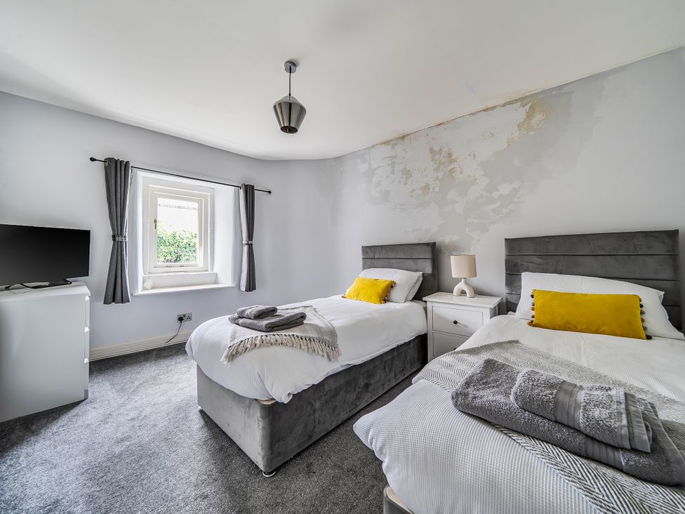 A bedroom with two beds and a television at Cosy Apartment above Village Pub in Taddington