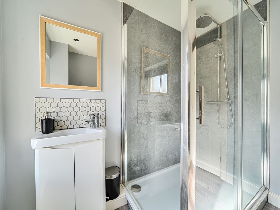 A bathroom with a shower, sink, and mirror at Cosy Apartment above Village Pub in Taddington