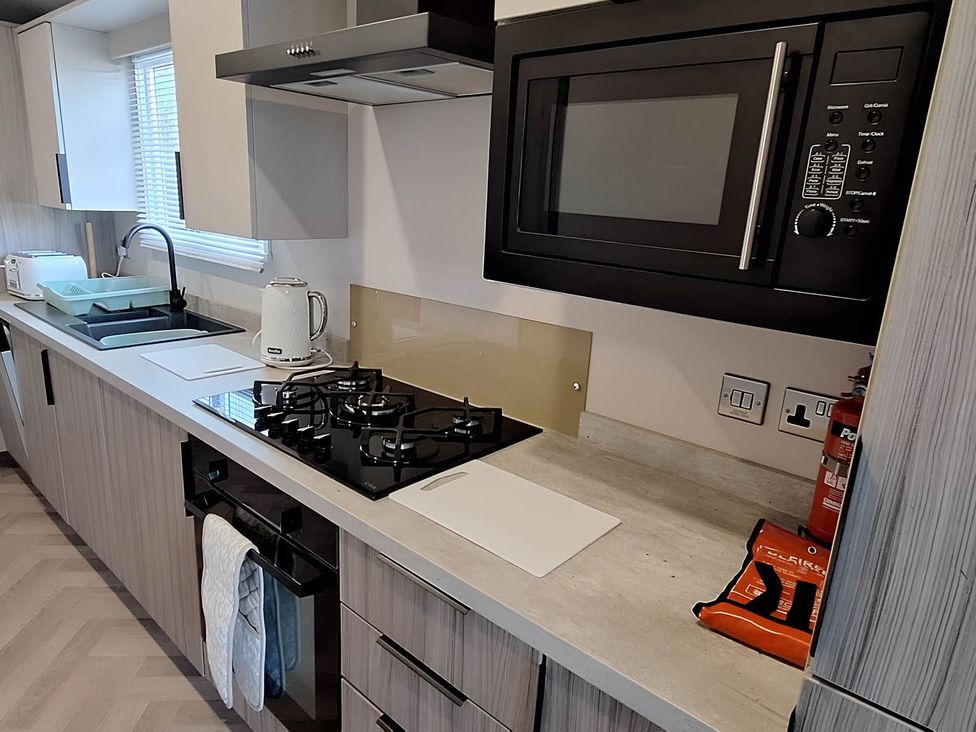 A kitchen with a gas stove and microwave oven at Tranquil Lodge Retreat in Paignton
