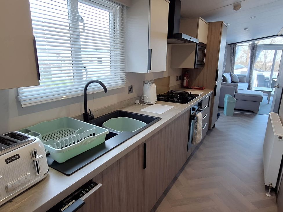 A kitchen with sink, appliances, and cabinets at Tranquil Lodge Retreat in Paignton