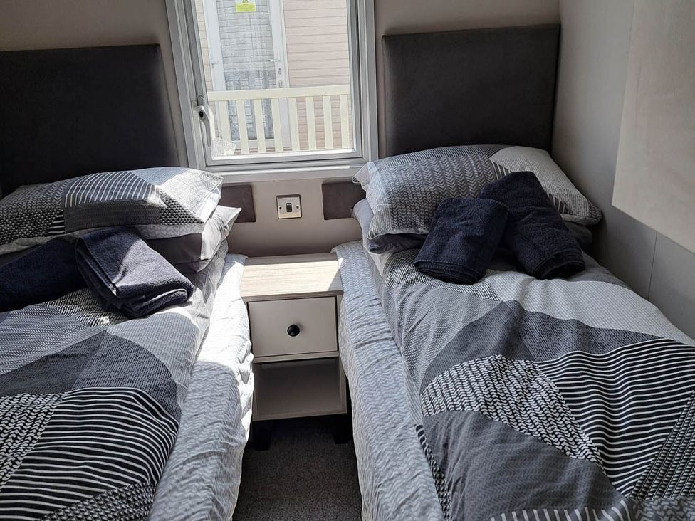 A bedroom with twin beds and a bedside table at Tranquil Lodge Retreat in Paignton