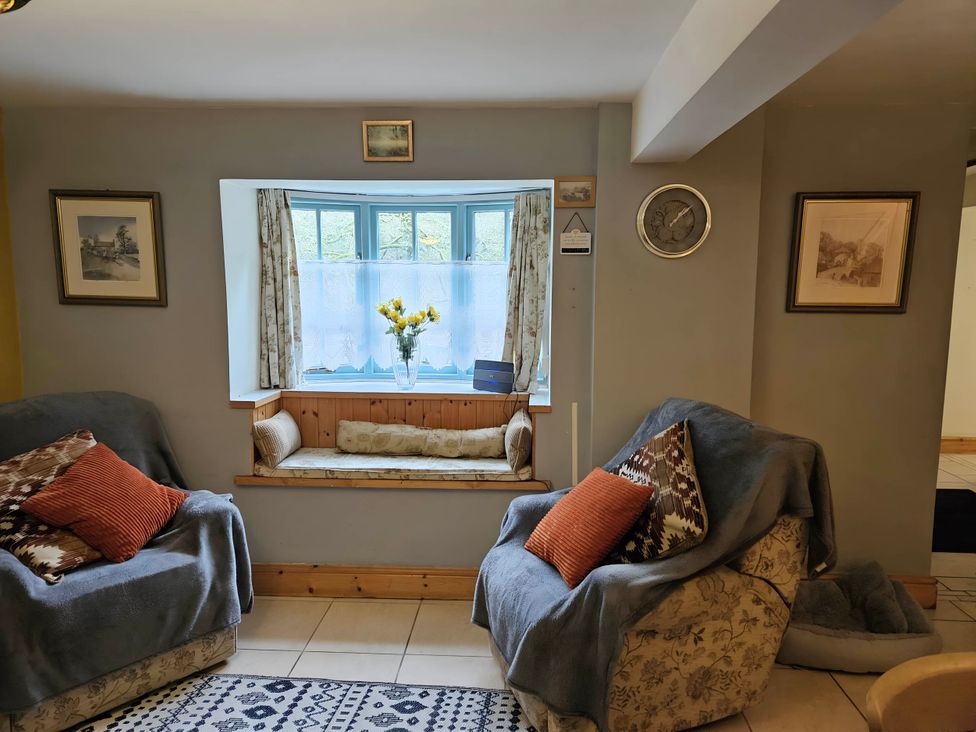 A living room with sofas and a window displaying flowers at Rose Cottage - Cosy cottage in Millers Dale