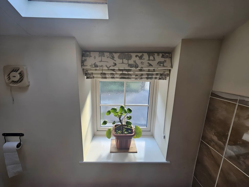 A bathroom with a plant on a windowsill at Rose Cottage - Cosy cottage in Millers Dale