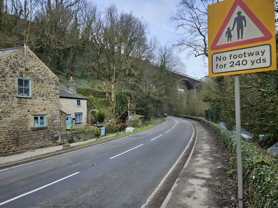 A rural scene with a house near a road and a sign at Rose Cottage - Cosy cottage in Millers Dale Chapel-En-Le-Frith