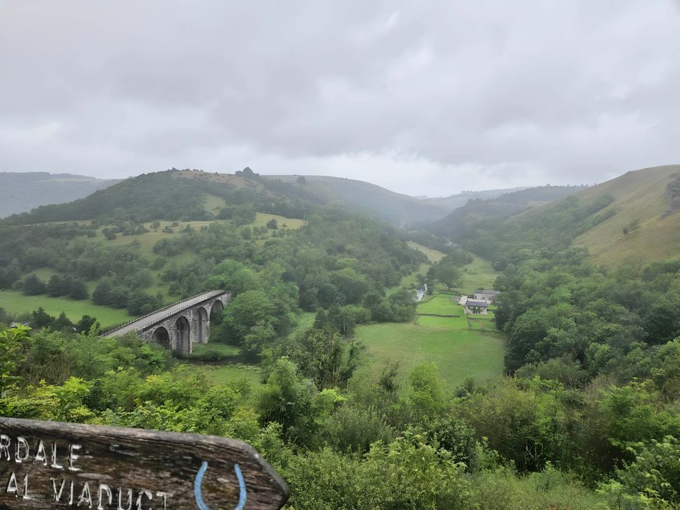A view of a viaduct over a river surrounded by hills and trees at Rose Cottage - Cosy cottage in Millers Dale