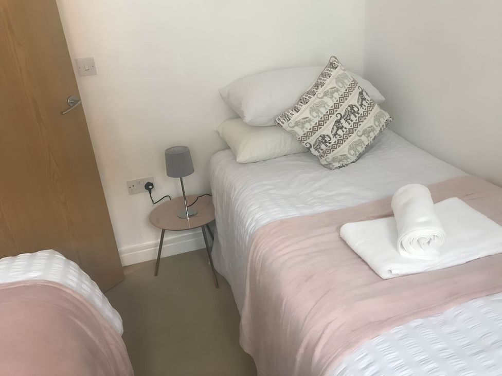 A bedroom with two single beds and a bedside table with lamp at 2-Bed Apartment Sleeps 4 with Garden