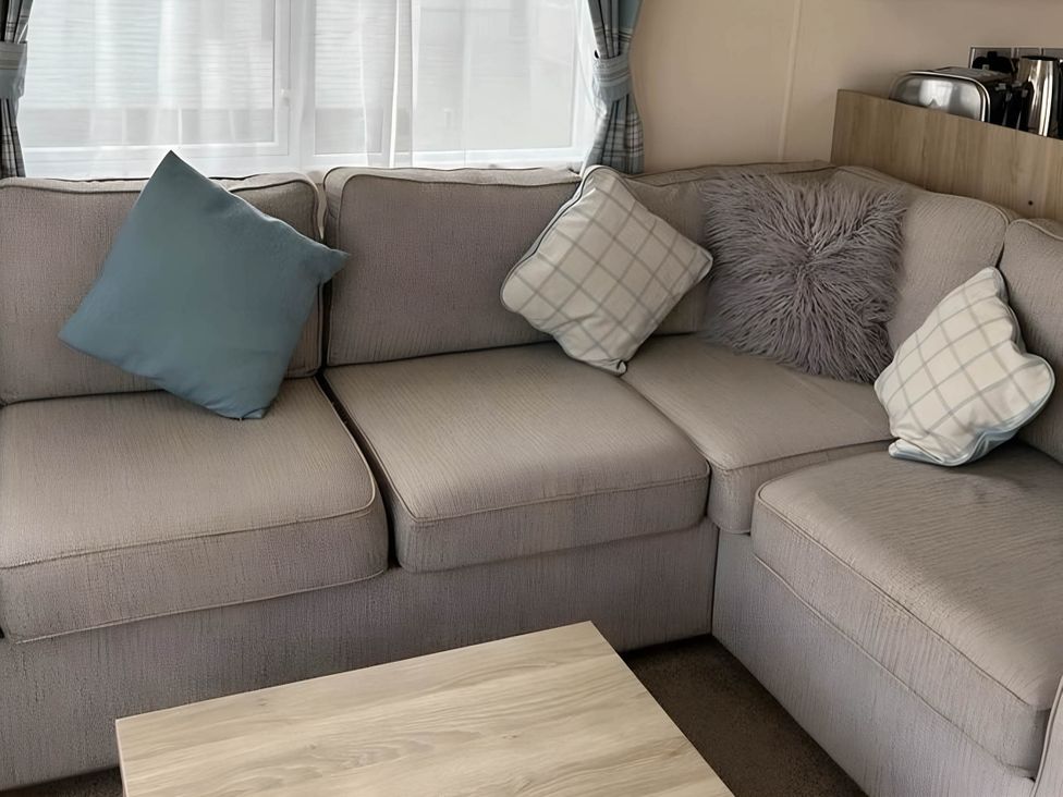 A living room with a sofa and cushions at Beautiful Static Caravan Hoburne Devon Bay