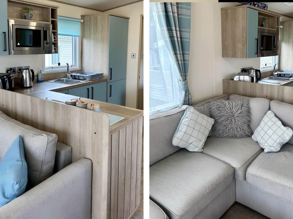 A kitchen area with microwave and sink and a living area with sofa at Beautiful Static Caravan Hoburne Devon Bay