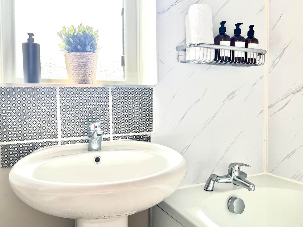 A bathroom with a sink and shelves for bath products at Central Ellesmere - Stay 2 - Parking - PetFriendly