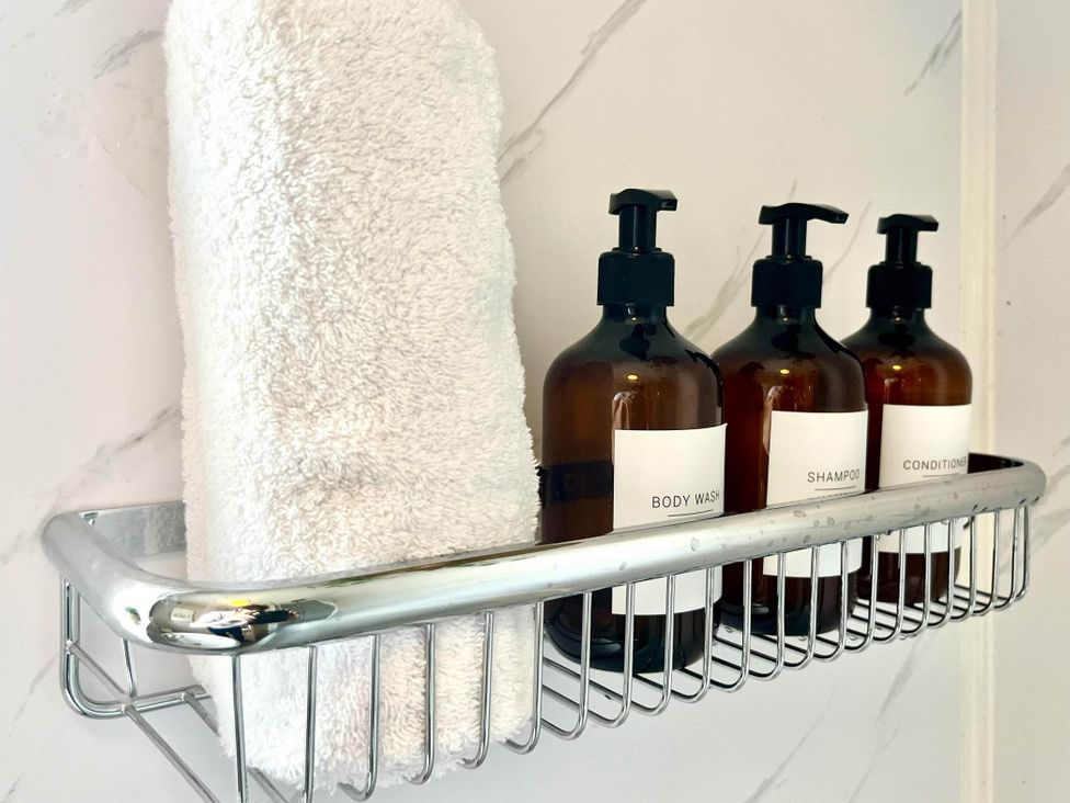 A towel and bottles of body wash, shampoo, and conditioner on a shelf in a bathroom