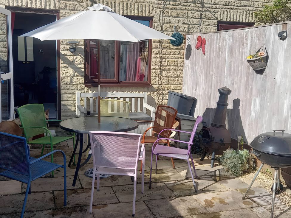A garden with a table and colorful chairs at 2 Bed House - Sleeps 6 - Pets - Garden - Parking