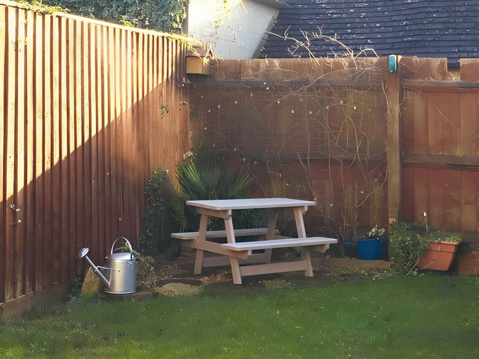A garden with a picnic table and watering can at 2 Bed House - Sleeps 6 - Pets - Garden - Parking