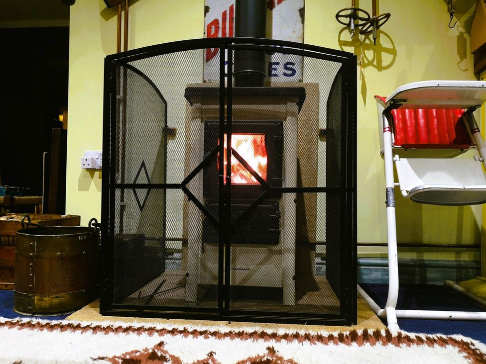 A wood stove behind a screen in a living room with a rug at Family Country Cottage with a private Valley View