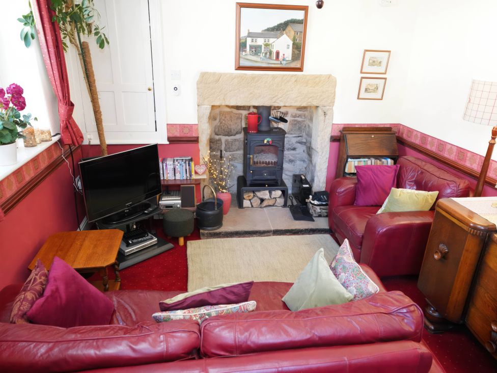 A living room with a fireplace and sofa at Traditional 2 Bedroom Cottage in Eyam, Hope Valley