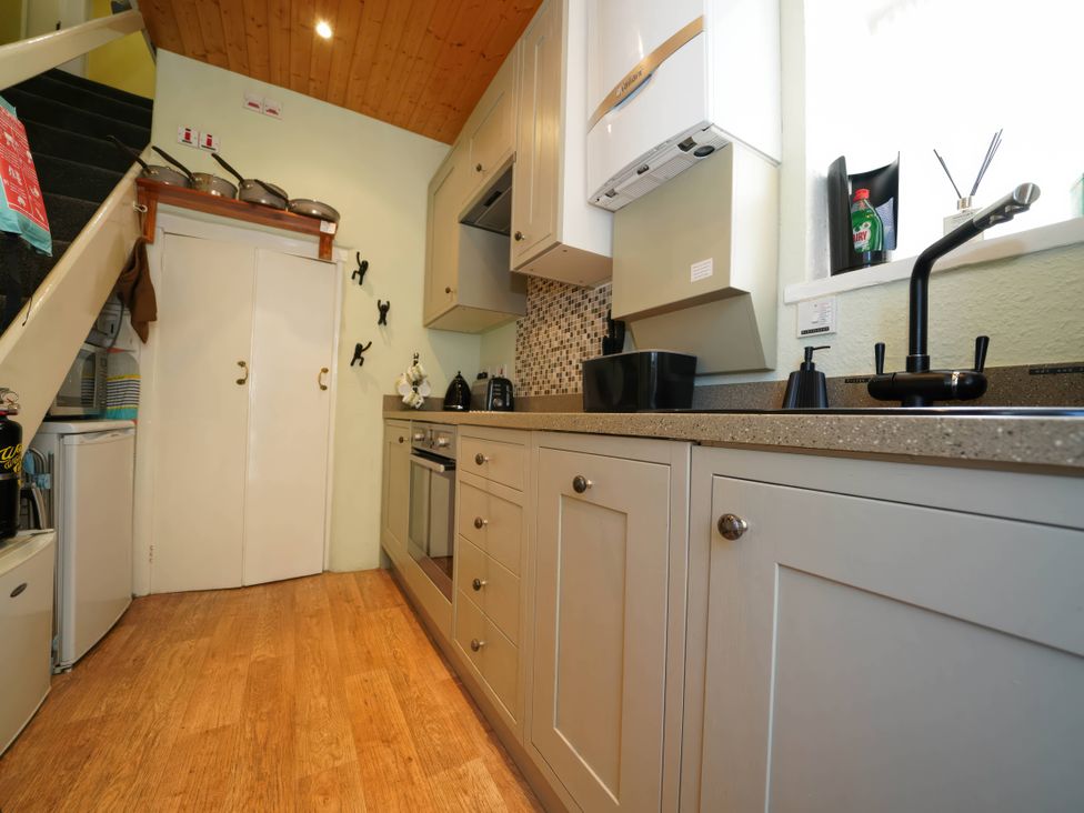 A kitchen with cabinets, stove and sink at Traditional 2 Bedroom Cottage in Eyam, Hope Valley