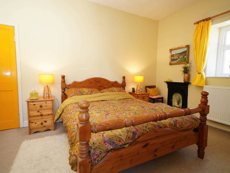 A bedroom with a wooden bed and yellow curtains at Traditional 2 Bedroom Cottage in Eyam, Hope Valley