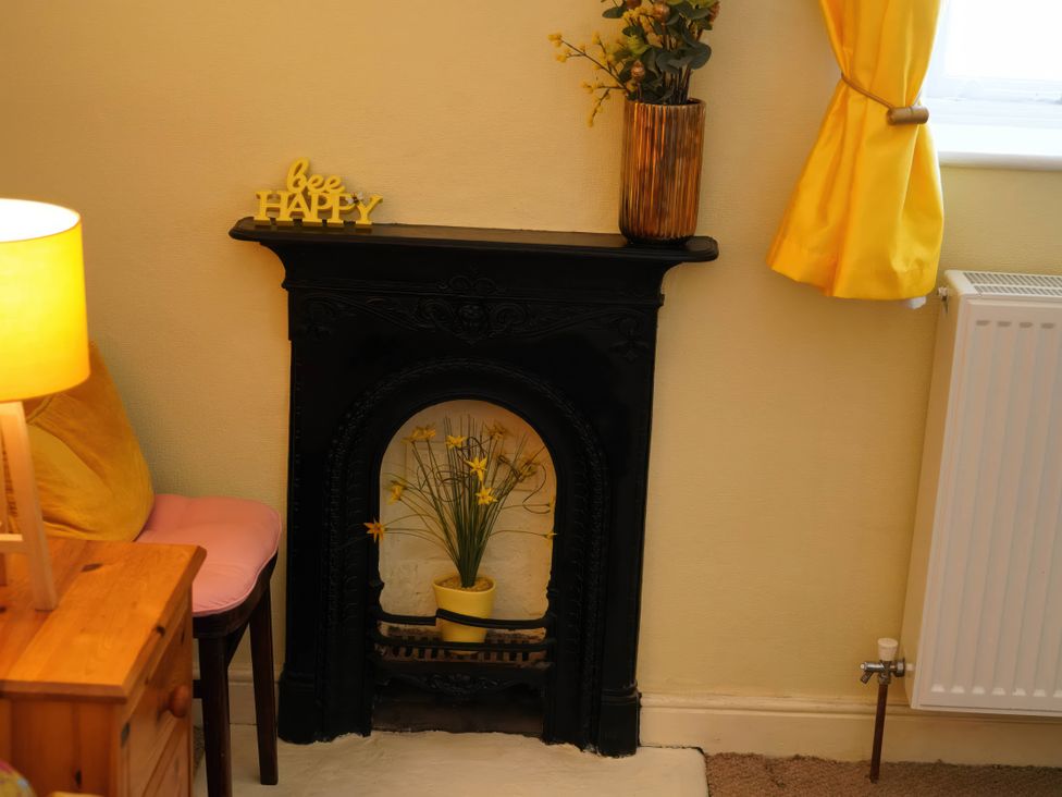 A living room with a fireplace and flower pot at Traditional 2 Bedroom Cottage in Eyam, Hope Valley