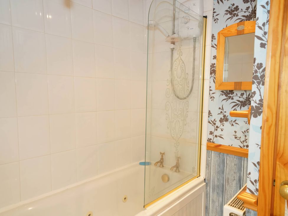 A bathroom with a shower over a bathtub and wooden mirror at Traditional 2 Bedroom Cottage in Eyam, Hope Valley