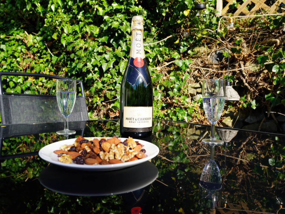An outdoor dining area with a wine bottle and glasses at Traditional 2 Bedroom Cottage in Eyam, Hope Valley