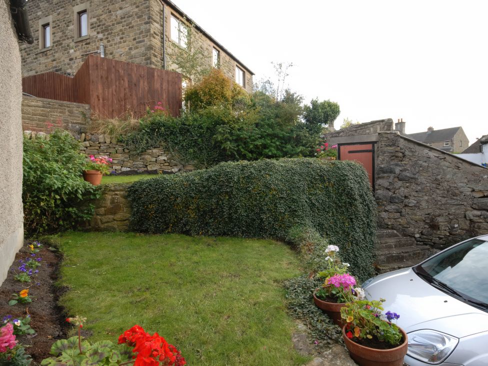 A garden with flower pots and a car at Traditional 2 Bedroom Cottage in Eyam, Hope Valley