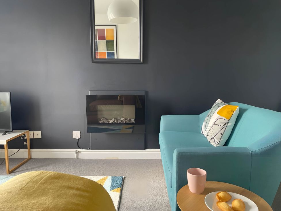 A living room with a teal sofa and a television at 2-Bed Flat in Summerbridge Harrogate, Pet Friendly