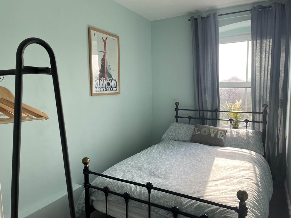 A bedroom with a bed, clothes rack, poster, and window at 2-Bed Flat in Summerbridge Harrogate, Pet Friendly