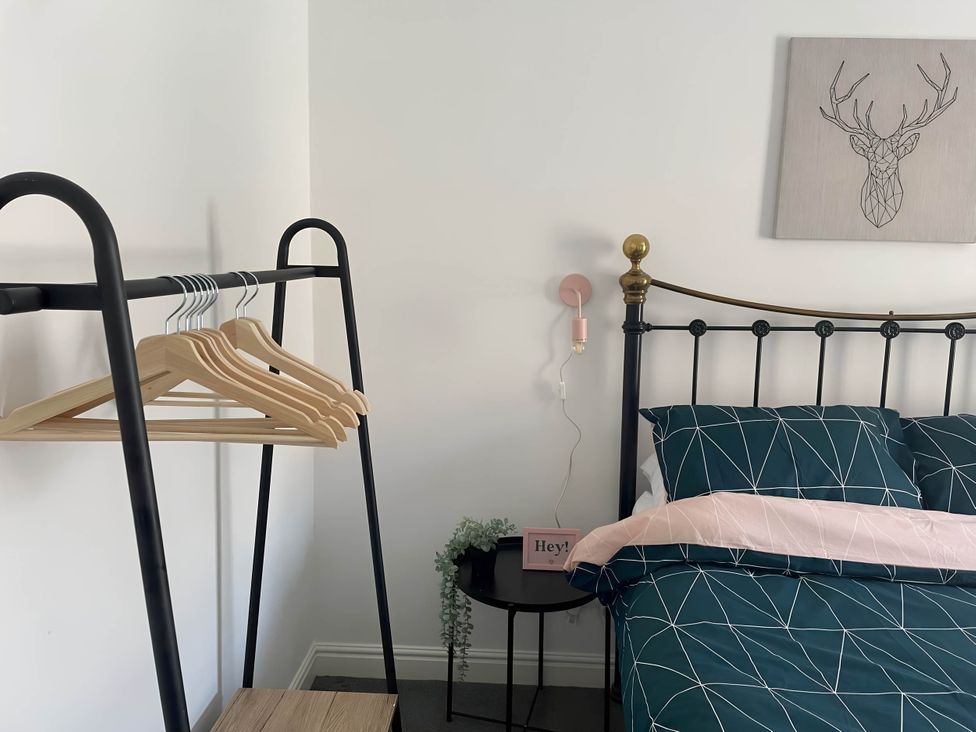 A bedroom with a bed, clothes rack and wall art at 2-Bed Flat in Summerbridge Harrogate, Pet Friendly