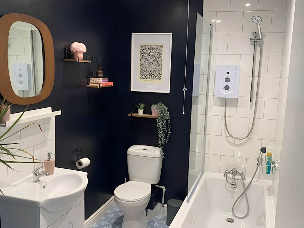 A bathroom with a mirror, sink, toilet, and bathtub at 2-Bed Flat in Summerbridge Harrogate, Pet Friendly